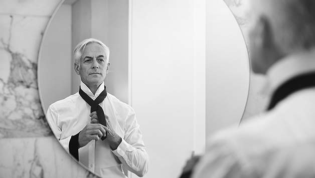 man tying his tie in a mirror